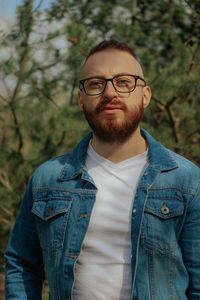 Portrait of young man standing against trees