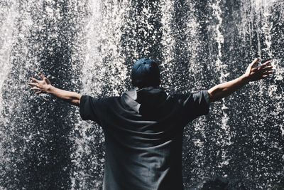 Rear view of man with arms outstretched standing on road