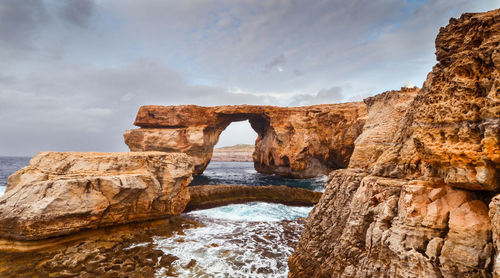 Rock formations by sea against sky