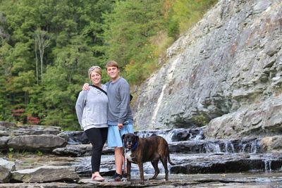 Mother and son standing by rural river in kentucky with family rescue dog