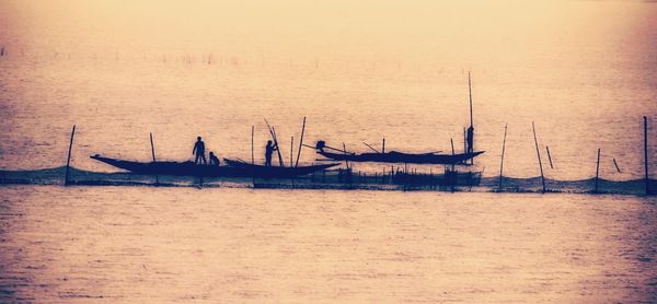 Boats sailing in sea against sky during sunset