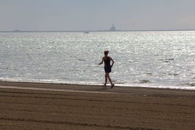 Full length of young woman standing on beach