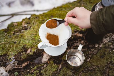 Making pour over coffee outdoors at a hiking trip. hand pouring ground coffee into a paper filter