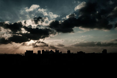 Silhouette buildings against sky at sunset