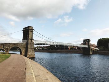 Bridge over river against cloudy sky