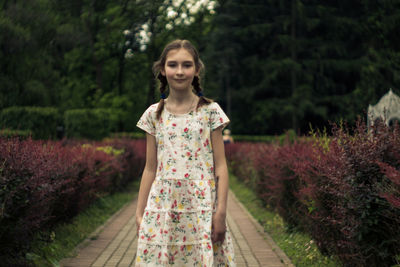 Portrait of smiling young woman standing against trees