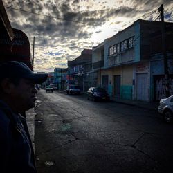 Man standing on road against cloudy sky