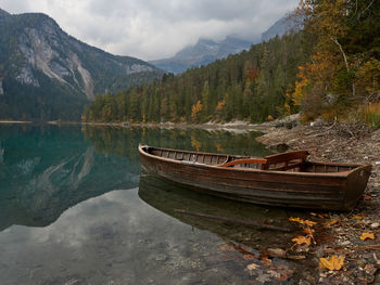 Boat moored on lake by mountains against sky