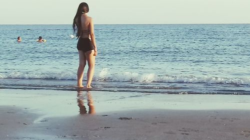 Full length of young woman standing on beach