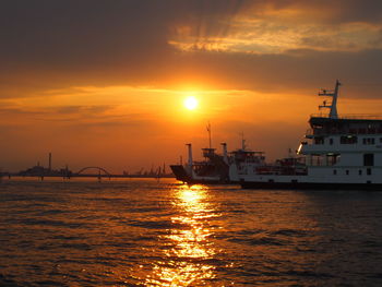 Silhouette ship in harbor against sky during sunset