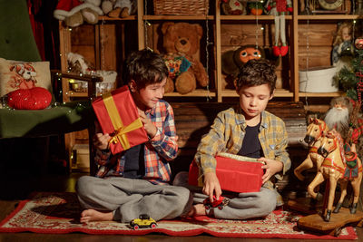 Two real brothers lie in a room with new year's decor near an armchair and look at gifts