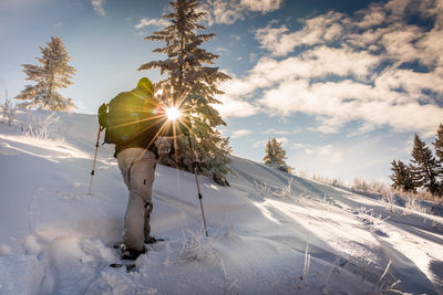 Man hiking on snowy mountain against sky