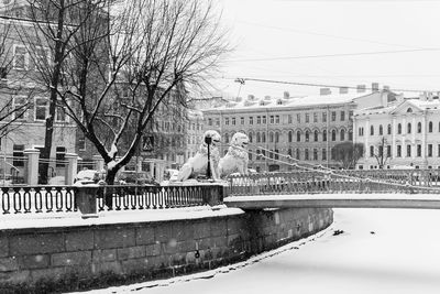 Bridge over canal amidst buildings against sky during winter