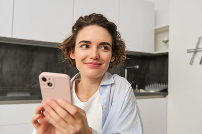 Portrait of young woman using mobile phone at home