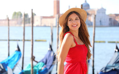 Portrait of beautiful young woman standing against water