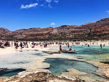 Group of people on beach against blue sky