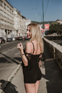 Rear view of woman with blond hair standing in city