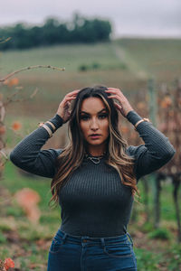 Portrait of beautiful young woman standing on field