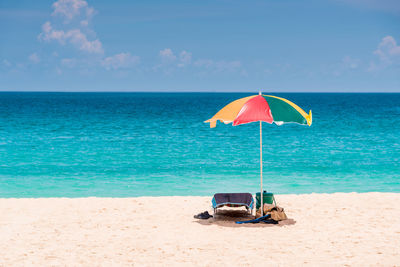 Deck chairs on beach against sky