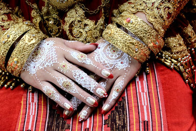 Midsection of woman with heena tattoo on hands