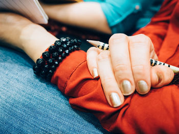 Midsection of woman holding pencil and book