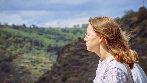 Young woman looking away against mountain