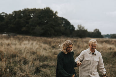 Women standing on field against trees