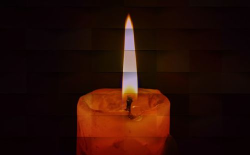 Close-up of lit candle against black background