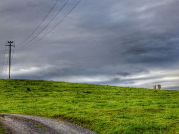 Scenic view of grassy field against cloudy sky