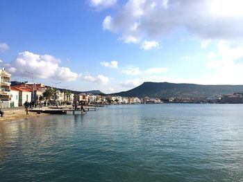 City at waterfront against cloudy sky