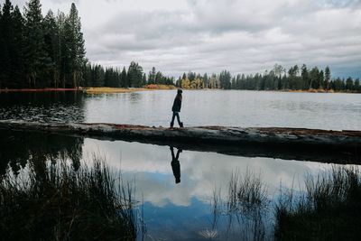 Girl walking by lake against sky