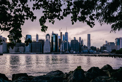 River and buildings against sky at dusk