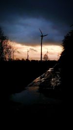 Silhouette of windmill on road against sky at sunset