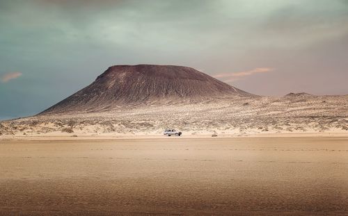 4x4 jeep driving on sandy beach under volcano at la graciosa, canary islands