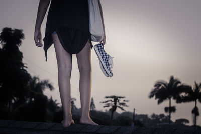 Low section of woman walking on footpath against sky