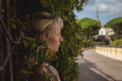 Side view of young woman against trees