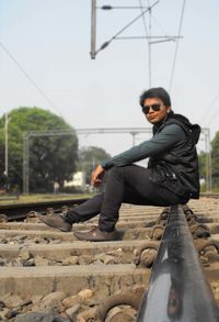 Full length of young man sitting on railroad track