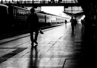 Rear view of man walking on railroad station platform