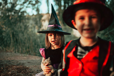 Portrait of boy holding hat in forest