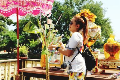 Full length of woman holding while standing against plants