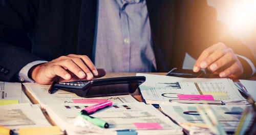 Midsection of businessman working on table