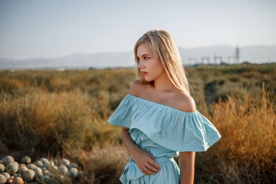 Teenage girl wearing dress standing on land against sky