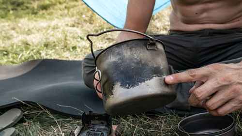 Midsection of man holding titanium cooking pot 