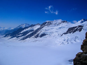 Scenic view of snowcapped mountains against blue sky