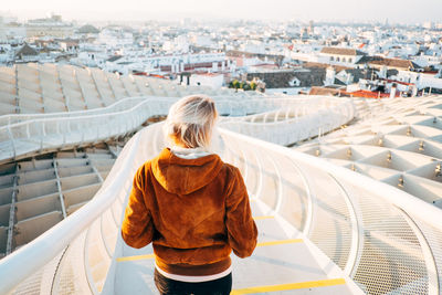 Rear view of woman standing in city against sky