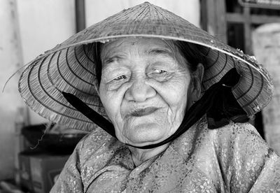 Woman wearing asian style conical hat while looking away at home