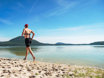 Shirtless man just in pants run in water at beach of sea in summer time. water cooling his body