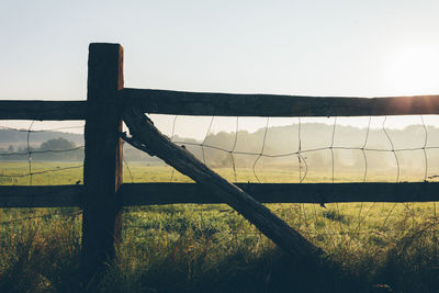 Wooden fence on grassy field during foggy weather in morning