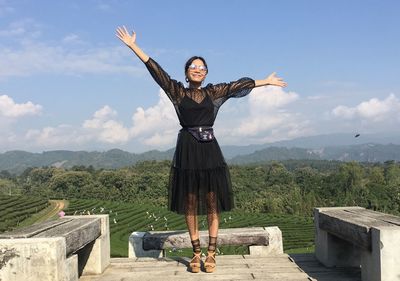 Rear view of woman with arms raised standing against wall