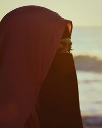 Close-up of young woman in hijab against sky during sunset